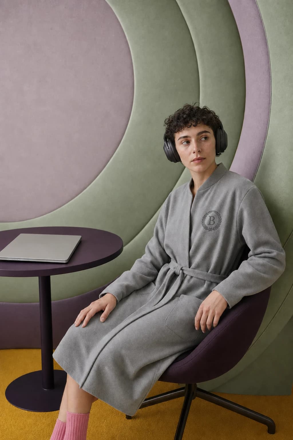 A person in the grey Muted Microfleece wears headphones inside a mint and lilac acoustic alcove.